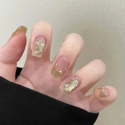 On-hand view of nude cat eye short squoval press-on nails with champagne shimmer, butterflies and pearl accents